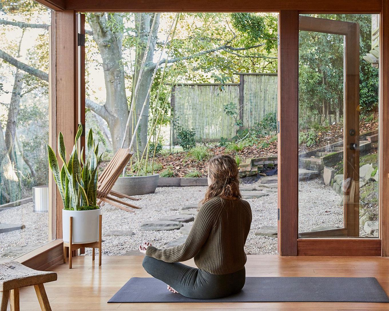 Woman practicing yoga in a relaxing room with plants